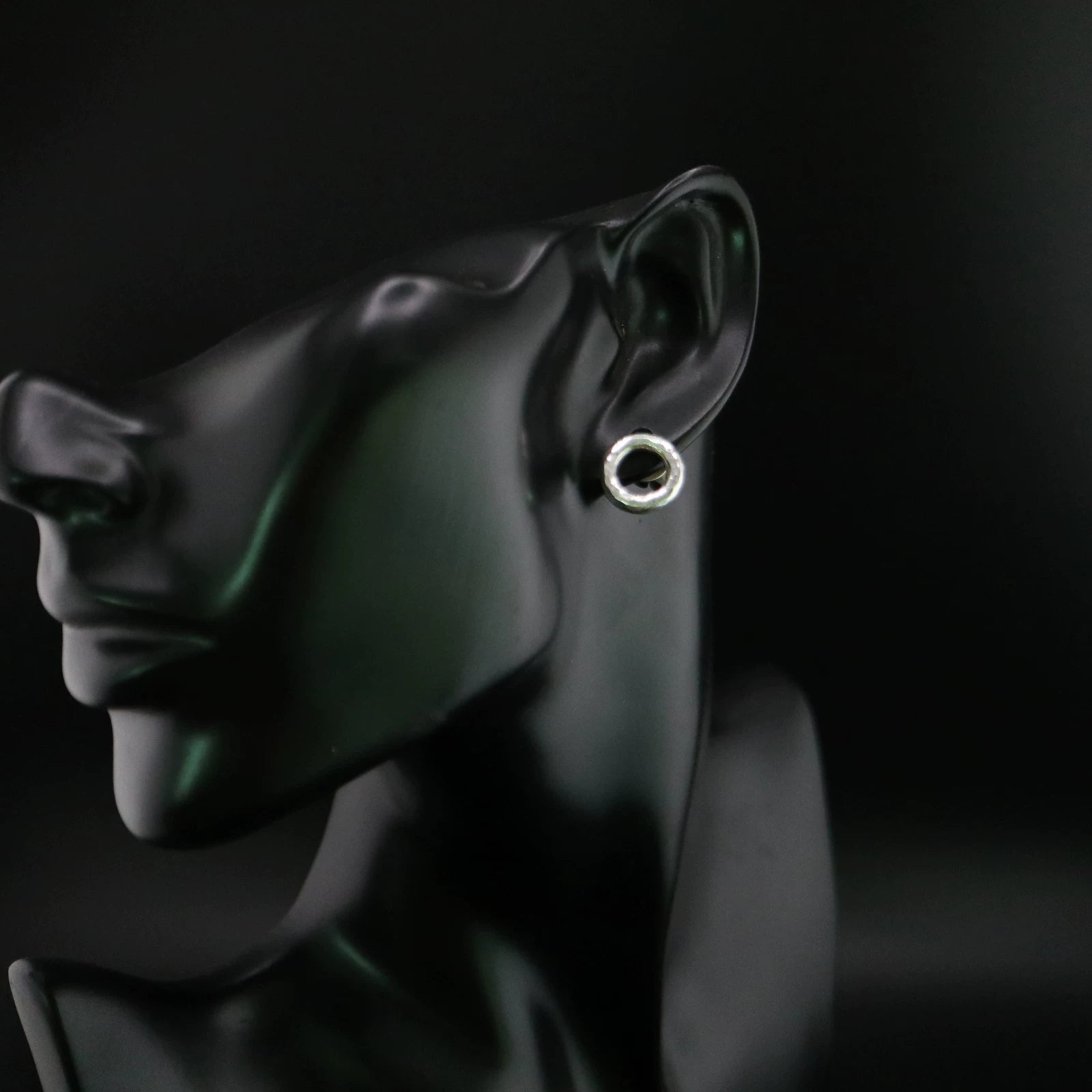 Handmade 925 sterling silver circular stud earrings with a hammered industrial texture and oxidized silver finish.