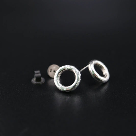 Handmade 925 sterling silver circular stud earrings with a hammered industrial texture and oxidized silver finish.