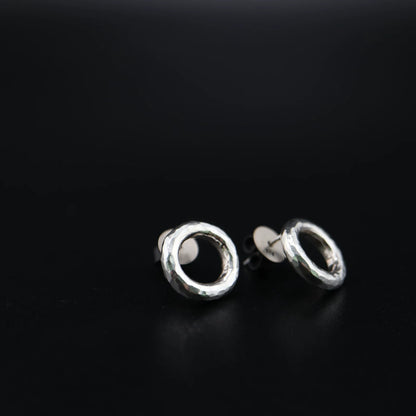 Handmade 925 sterling silver circular stud earrings with a hammered industrial texture and oxidized silver finish.
