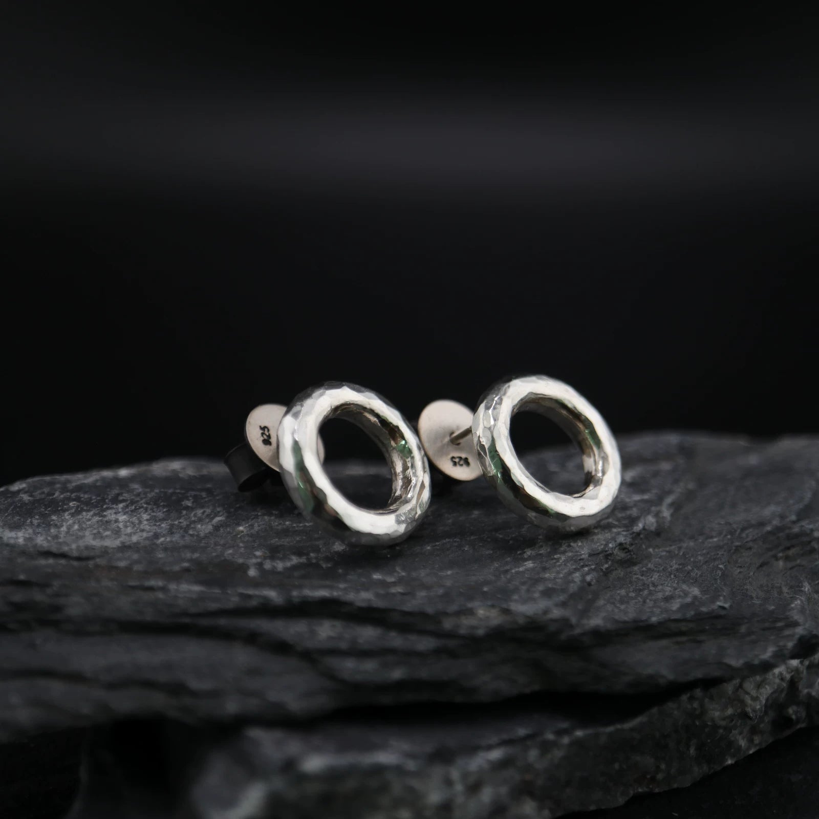 Handmade 925 sterling silver circular stud earrings with a hammered industrial texture and oxidized silver finish.