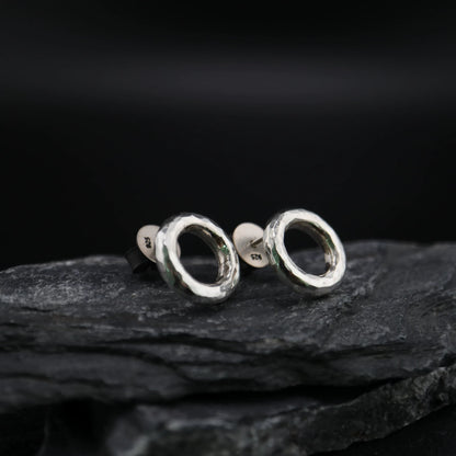 Handmade 925 sterling silver circular stud earrings with a hammered industrial texture and oxidized silver finish.